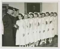 black & white photo of President Eisenhower shakes the hand of a newly graduated nurse